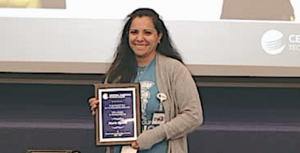 A young woman holds a commeorative plaque.