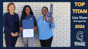 Three women stand in front of a white brick wall. The woman in the middle holds a certificate and the woman on the right has a large #1 foam finger. Text on the side reas "Top Titan, Lisa Shaw, 3rd quarter. 2026. and below that is the titan head CCTC logo.